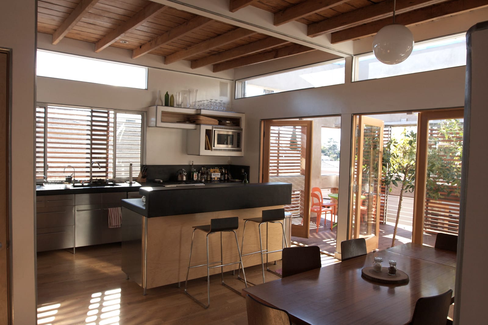 A kitchen with an island bench and daylight from the garden doors
