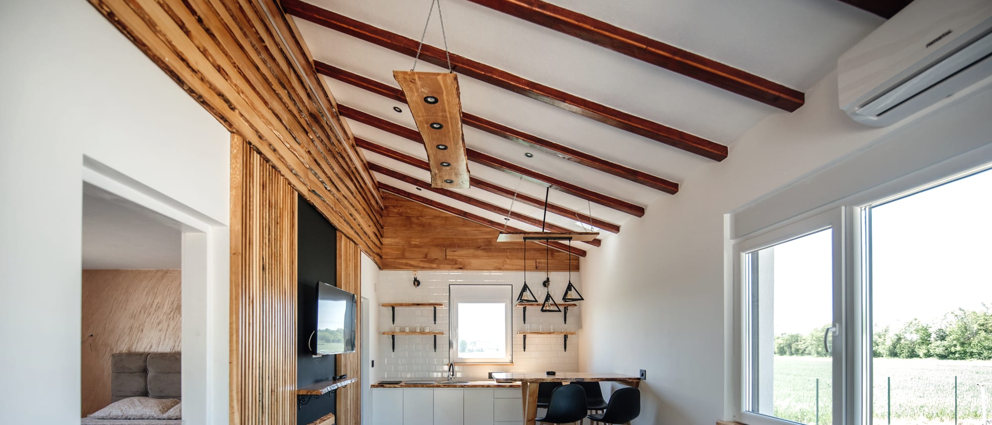 An open-plan living area with a timber ceiling and wide windows
